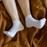 Füße mit weißen Socken auf brauner Decke die zeigen kalte Füße durch Schilddrüse