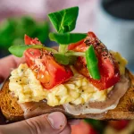 Ein Brot mit Schinken, Rührei, Tomaten und Salatblatt als Symbol für Rührei Kalorien